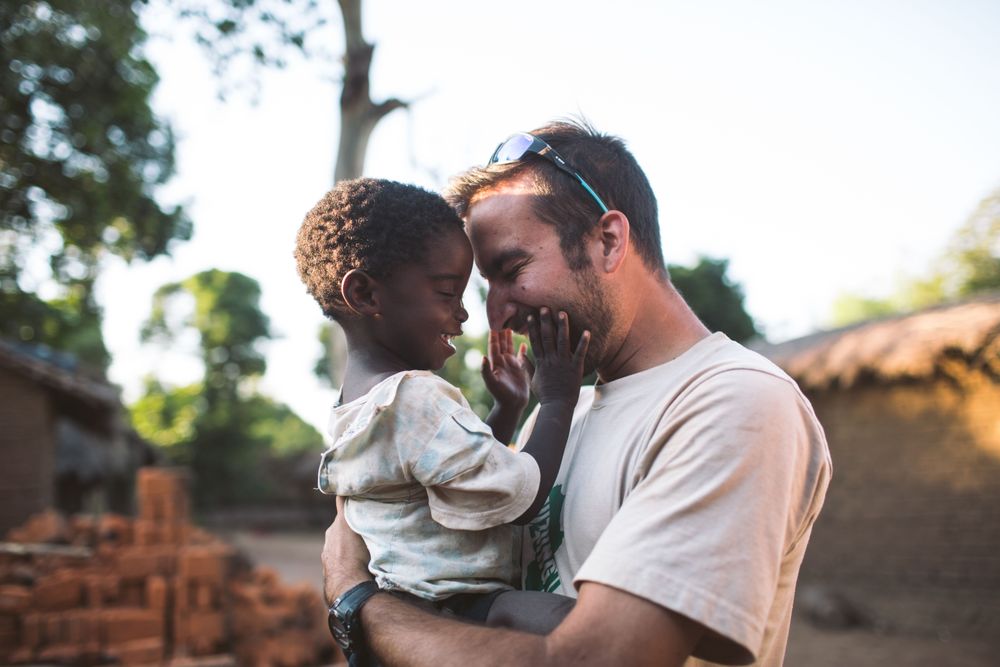 afbeelding man met kind Ghana omhelzing na delen goed nieuws evangelie zending missiewerker