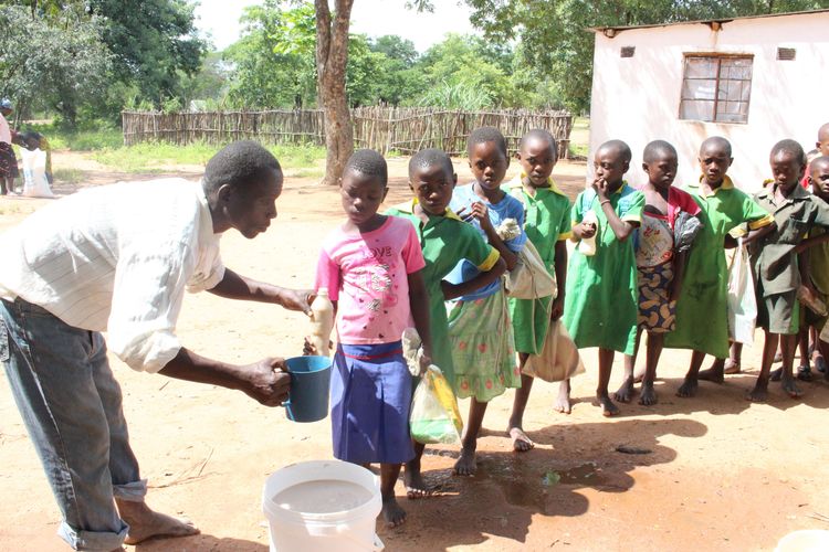A member of the Mulambe parent's committee serves the Mahewu drink to school children. In drought-hit Zimbabwe, schools are no longer just places to learn algebra and mathematics but are on the frontline to help feed children.