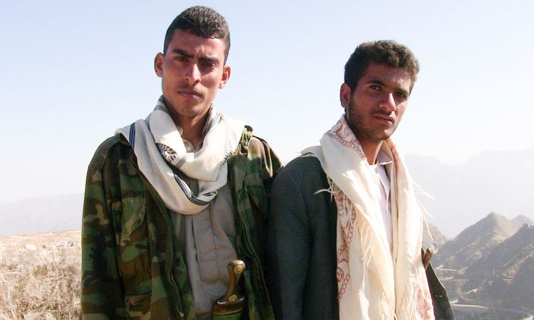 Two men in Yemen with traditional headgear cloths draped over their shoulders.