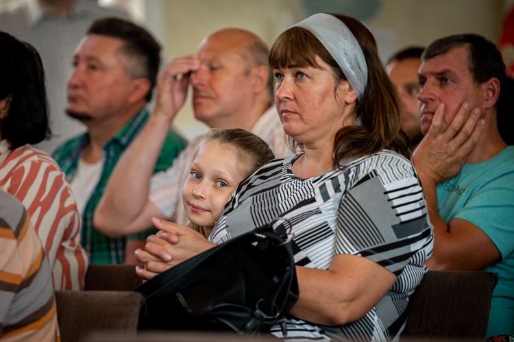 A young girl leans against her mother in a church in East Ukraine that shelters refugees and displaced people. Photo by Alex Coleman.