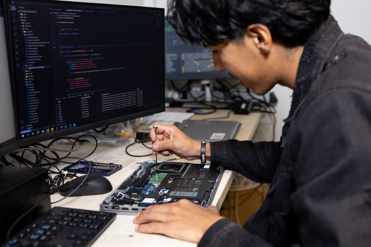 A man from Mexico takes apart a laptop to fix it. Photo by RJ Rempel.