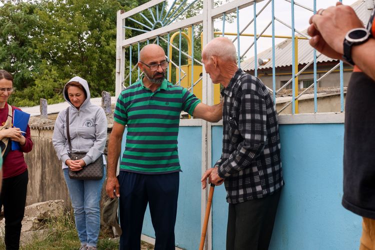An OM team member prays for an old man during a house visit. Photo by Jordan Wilkinson.