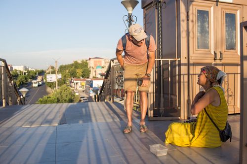 A team member talks to a homeless lady sitting near a stairway.