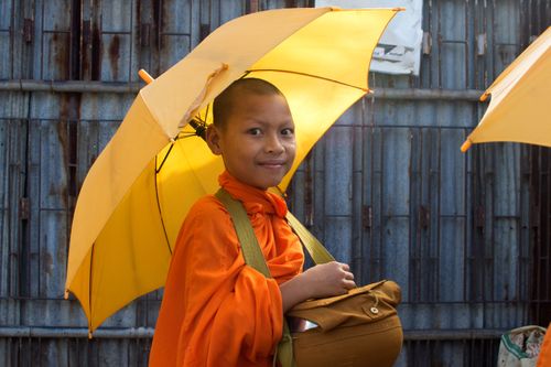 A young novice monk makes his morning rounds to collect alms - offering prayers in exchange for money and food gifts.