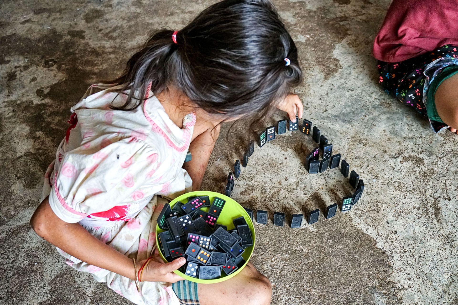 A young school girl in Myanmar playing with dominoes.