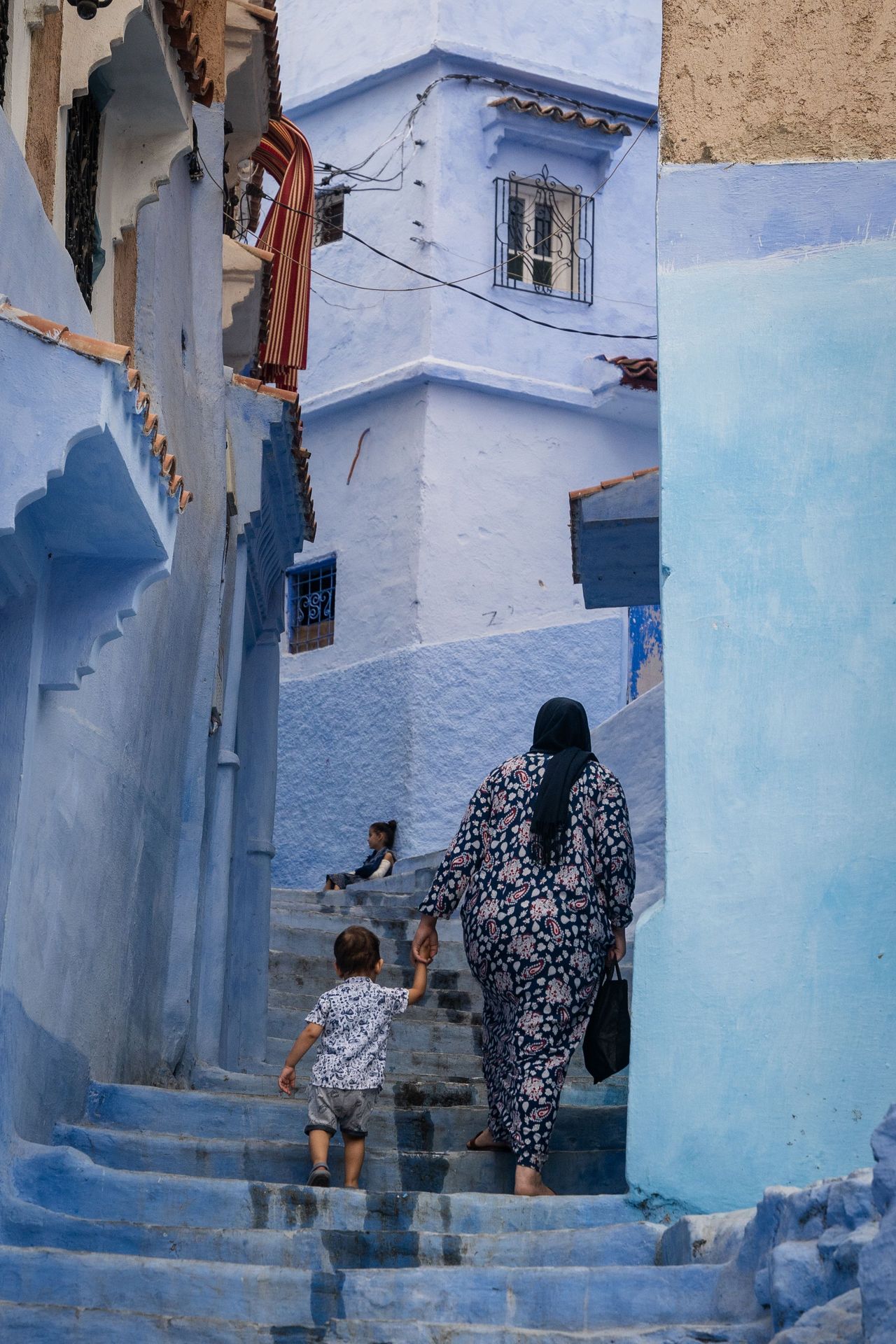 A woman holds the hand of a child and walks up stairs in Morocco. Photo by RJ Rempel.
