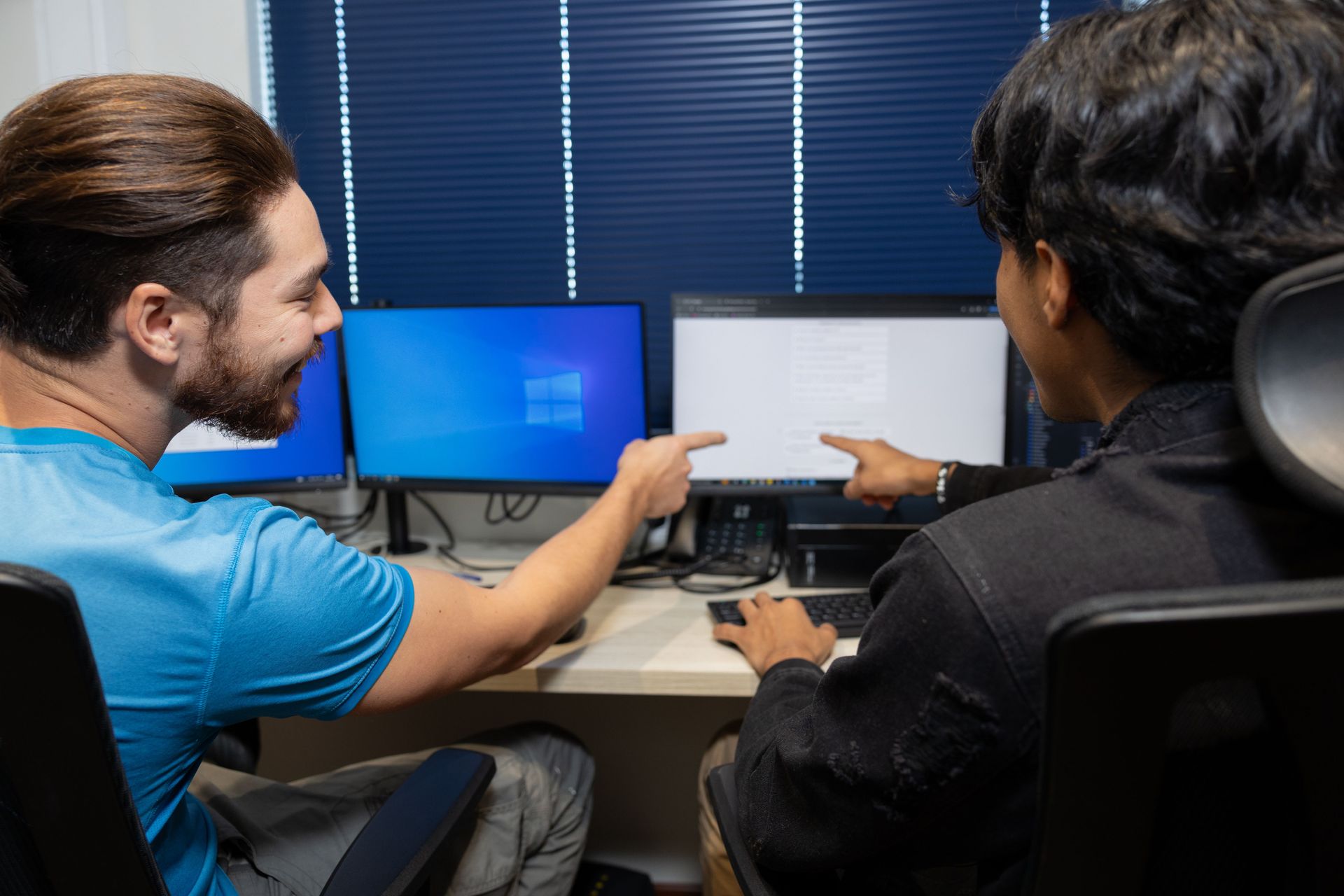 A man from Canada (left) and a man from Mexico work together in the IT office. Photo by RJ Rempel.