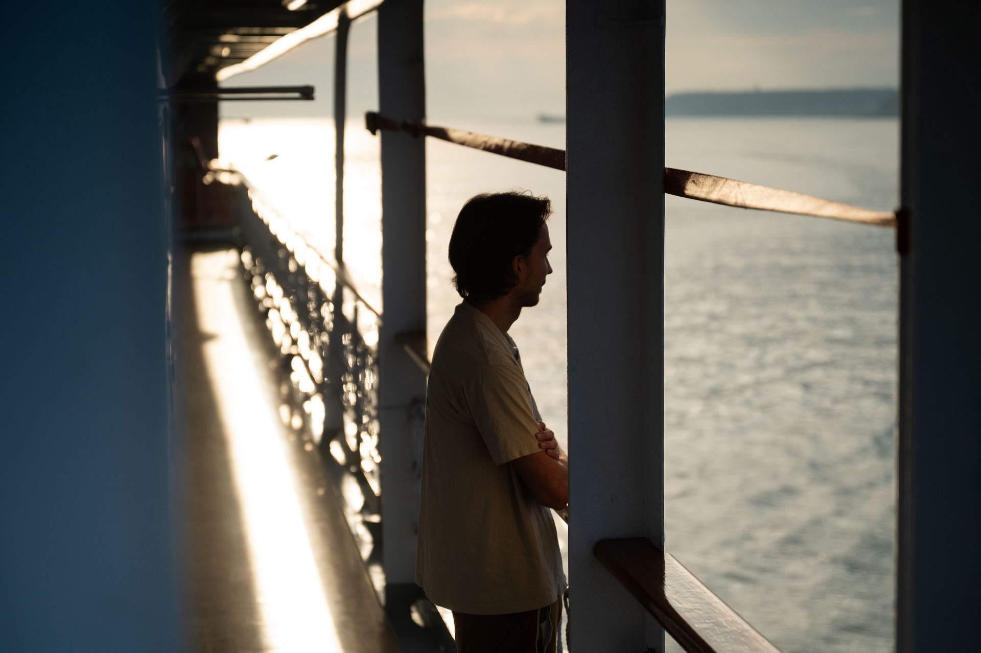 At Sea :: Josh (US) looks at the coast in the afternoon sun.