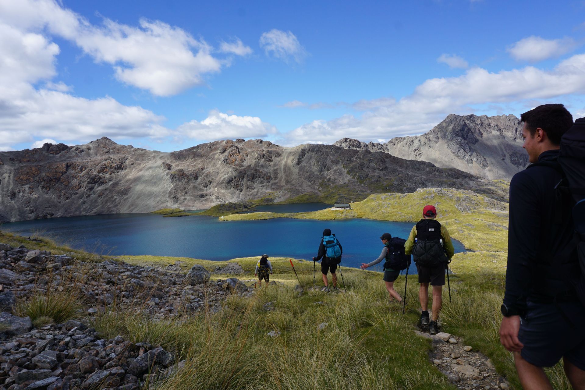 A group of young people hike in the New Zealand mountains. 